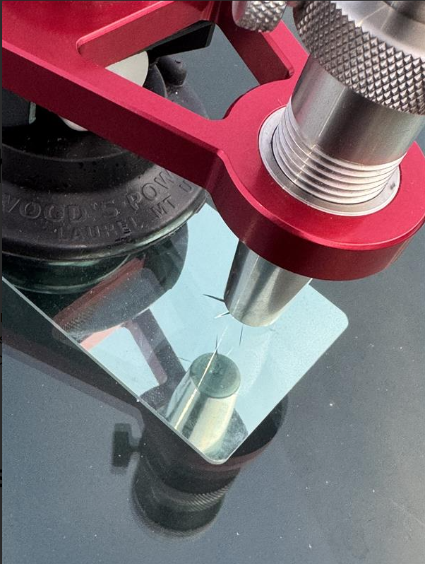 Red repair bridge tool clamped to a windshield over a rock chip