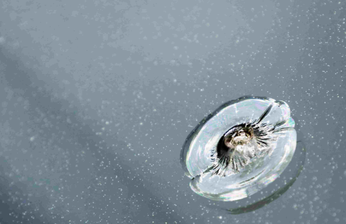 Close-up of a rock chip impact point in laminated windshield glass